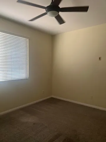 an empty room with a window and a fan