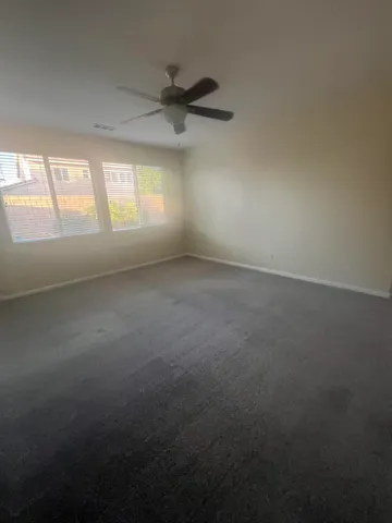 en empty room with windows and ceiling fan