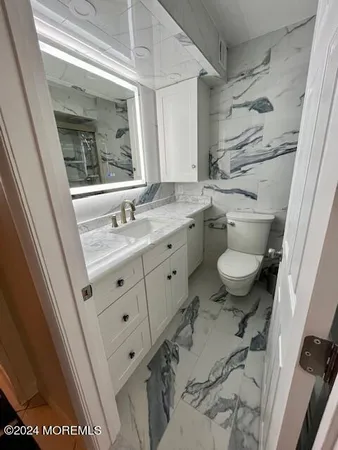a bathroom with a granite countertop sink toilet a mirror and shower