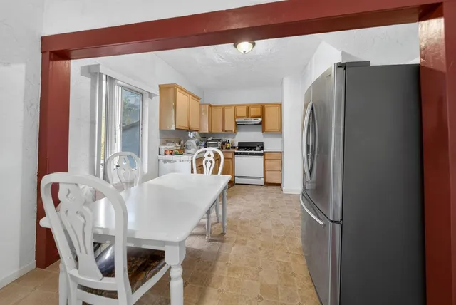 a kitchen with stainless steel appliances a refrigerator a stove a dining table and chairs with wooden floor