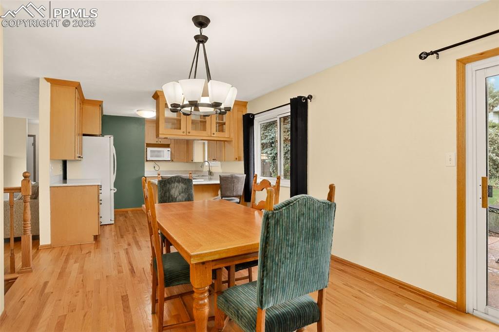 6035 Tuckerman Lane Colorado Springs, CO 80918 - Photo 18 of 47 a dining room with furniture a chandelier and wooden floor