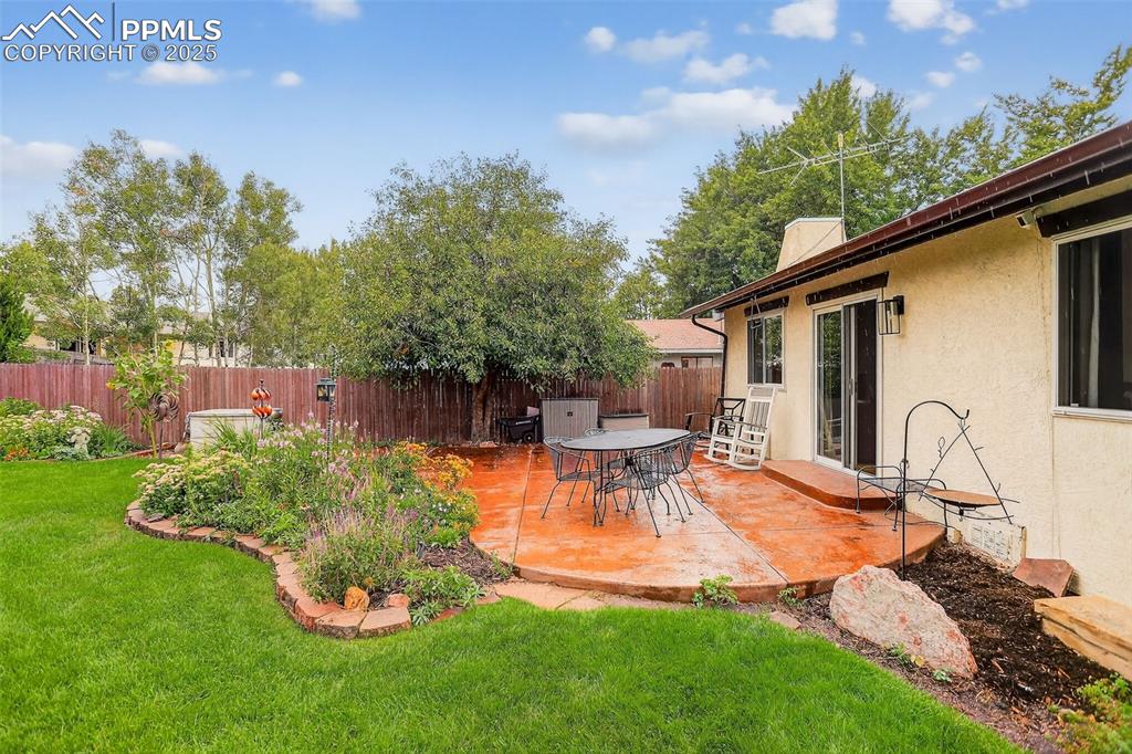 6035 Tuckerman Lane Colorado Springs, CO 80918 - Photo 39 of 47 a view of a backyard with table and chairs potted plants and a palm tree