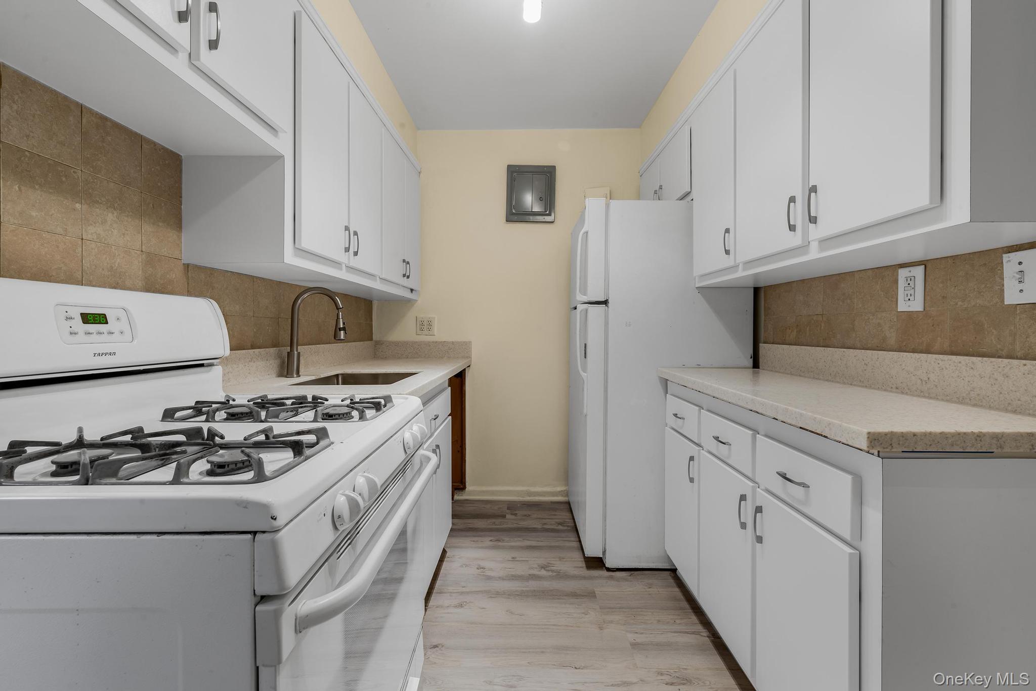 102-25 67th Road, Unit 3C Queens, NY 11375 - Photo 9 of 17 Kitchen with white appliances, tasteful backsplash, white cabinetry, and light wood-type flooring