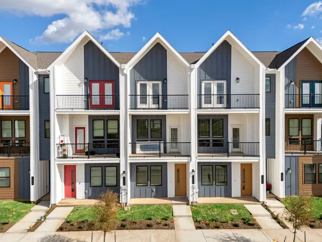 a front view of a residential apartment building with a yard and plants