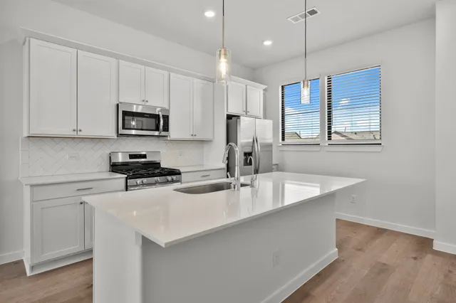 a kitchen with stainless steel appliances granite countertop a sink a stove a refrigerator a center island with wooden floor and cabinets