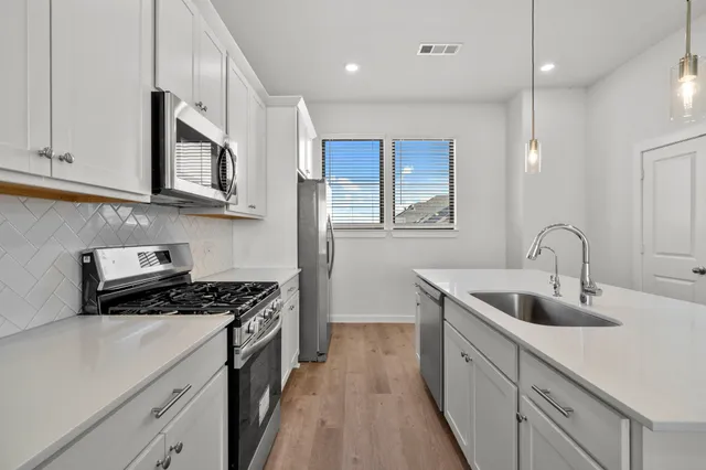 a kitchen with stainless steel appliances granite countertop a sink a stove and a refrigerator