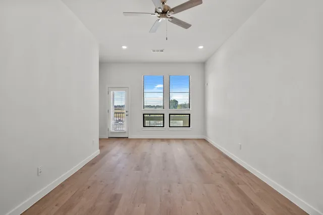 a view of an empty room with a window and wooden floor