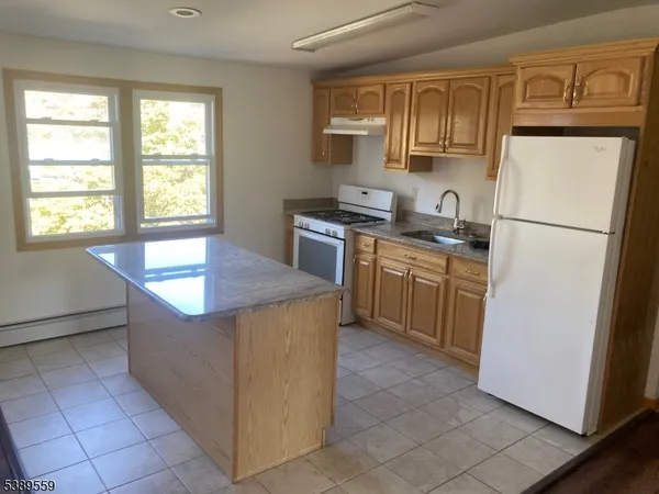 a kitchen with stainless steel appliances granite countertop a refrigerator sink stove and cabinets
