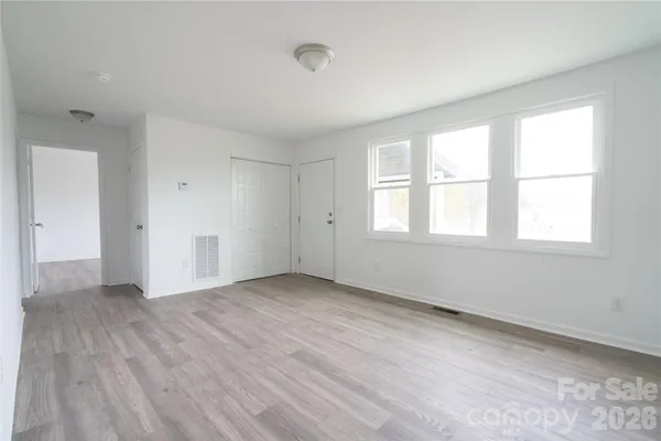 a view of an empty room with wooden floor and closet