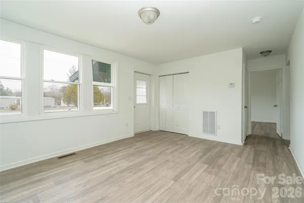 an empty room with stainless steel appliances kitchen island furniture and wooden floor
