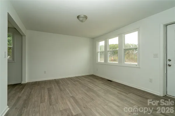 a view of an empty room with window and wooden floor