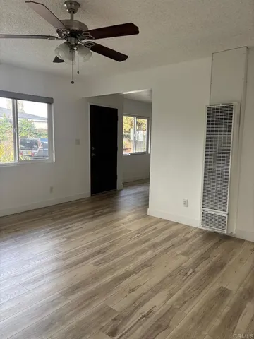 an empty room with wooden floor fan and windows
