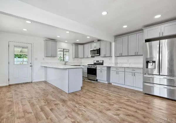a kitchen with stainless steel appliances granite countertop a refrigerator sink and white cabinets