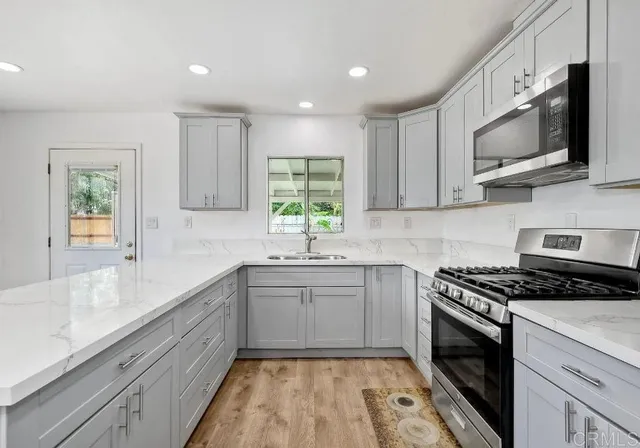 a kitchen with stainless steel appliances granite countertop a sink a stove a microwave and cabinets
