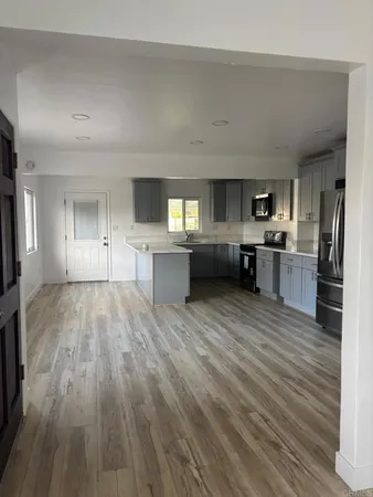 a large kitchen with cabinets wooden floor and stainless steel appliances