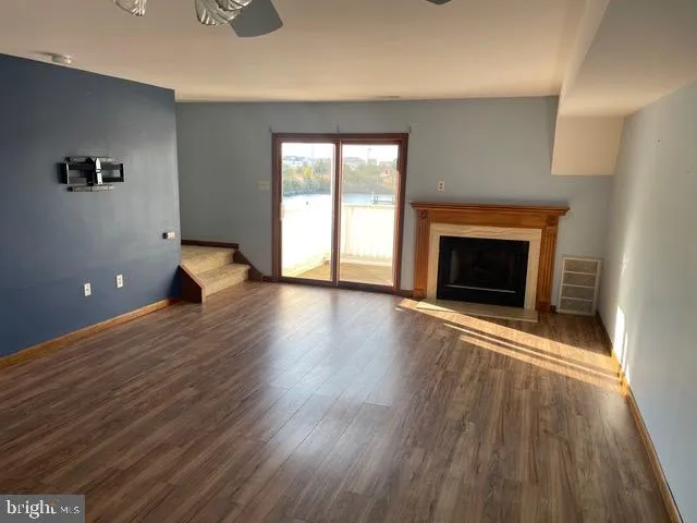 an empty room with wooden floor fireplace and windows
