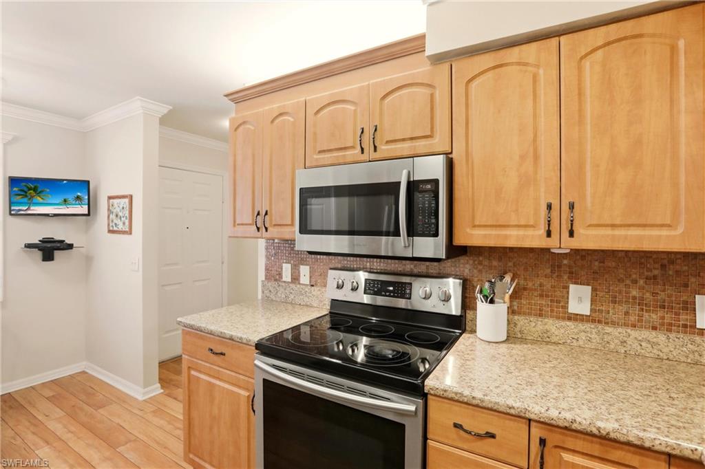 289 Robin Hood Circle, Unit 101 Naples, FL 34104 - Photo 12 of 47 a kitchen with stainless steel appliances granite countertop a stove a microwave and a refrigerator