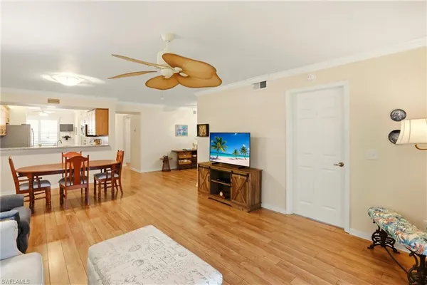 a living room with furniture kitchen view and a wooden floor