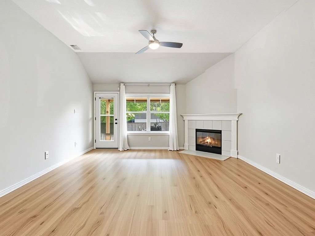 1201 Ridgewood Drive Leander, TX 78641 - Photo 4 of 29 Unfurnished living room featuring light wood-style flooring, lofted ceiling, a tile fireplace, and ceiling fan