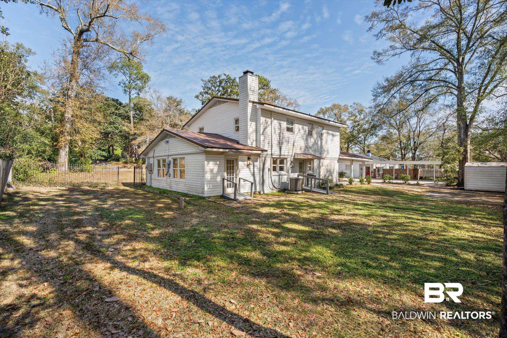 3933 Radnor Avenue Mobile, AL 36608 - Photo 29 of 36 Back of property featuring a fenced backyard, a chimney, a carport, metal roof and a shed