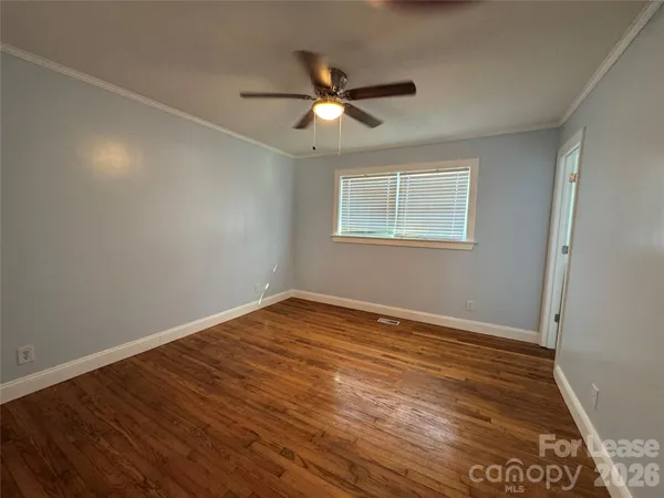 an empty room with wooden floor ceiling fan and windows