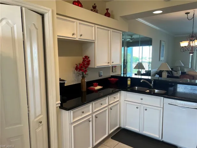 a kitchen with granite countertop a refrigerator a stove and white cabinets with wooden floor