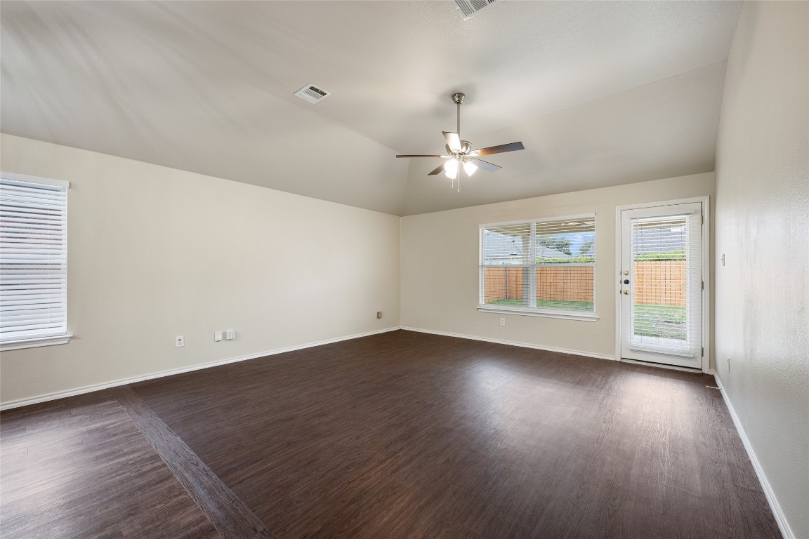 4009 Veiled Falls Drive Pflugerville, TX 78660 - Photo 15 of 26 an empty room with wooden floor chandelier fan and windows