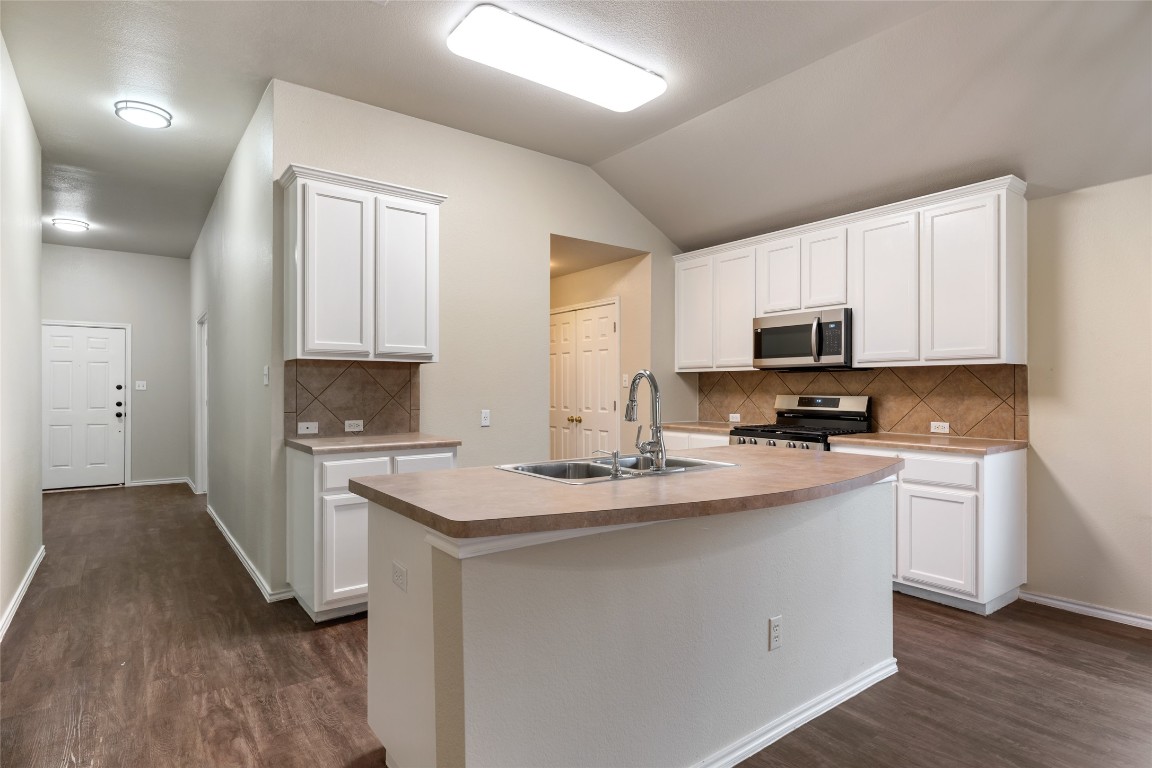 4009 Veiled Falls Drive Pflugerville, TX 78660 - Photo 7 of 26 a kitchen with stainless steel appliances a sink dishwasher a stove top oven a refrigerator with white cabinets and wooden floor