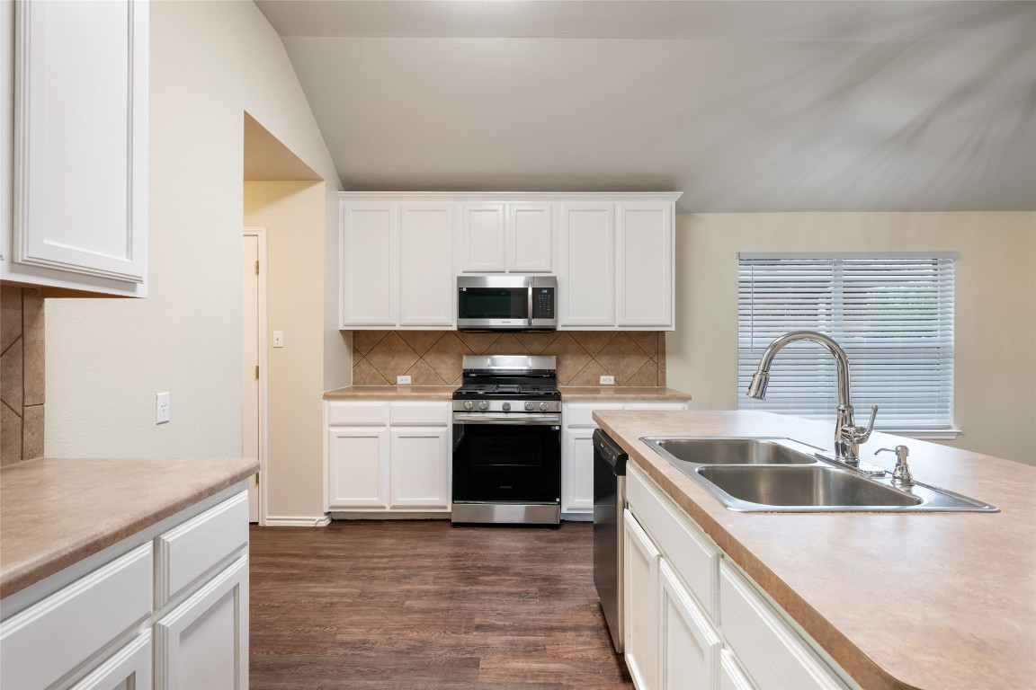 4009 Veiled Falls Drive Pflugerville, TX 78660 - Photo 9 of 26 a kitchen with stainless steel appliances granite countertop a sink and a stove top oven with wooden floor