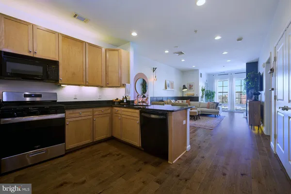 a kitchen with granite countertop a stove top oven a sink dishwasher a dining table and chairs with wooden floor