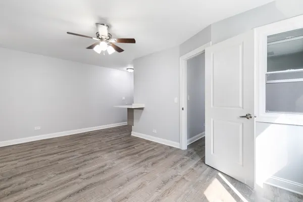 an empty room with wooden floor fan and windows