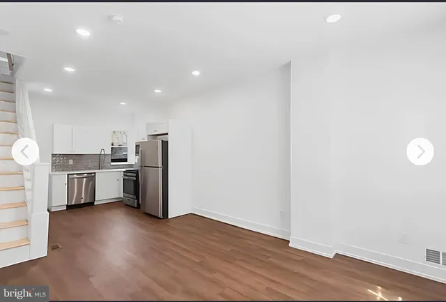 a kitchen with stainless steel appliances a refrigerator and wooden floor