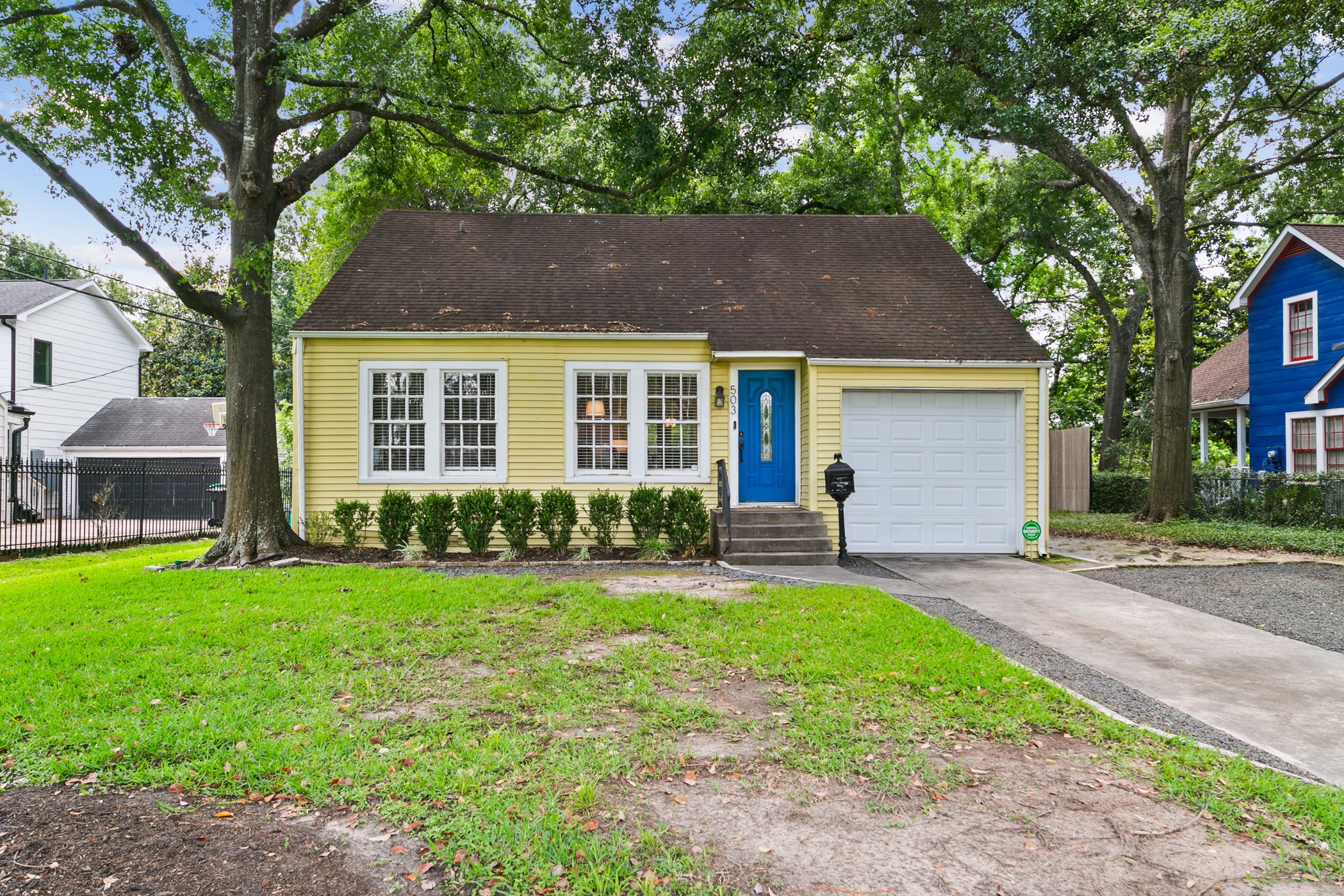 503 West 33rd Street Houston, TX 77018 - Photo 1 of 34 Charming house with a welcoming blue door, nestled among mature trees. Features a single-car garage, tidy front lawn, and a simple pathway leading to the entrance. Ideal for living in a picturesque neighborhood.