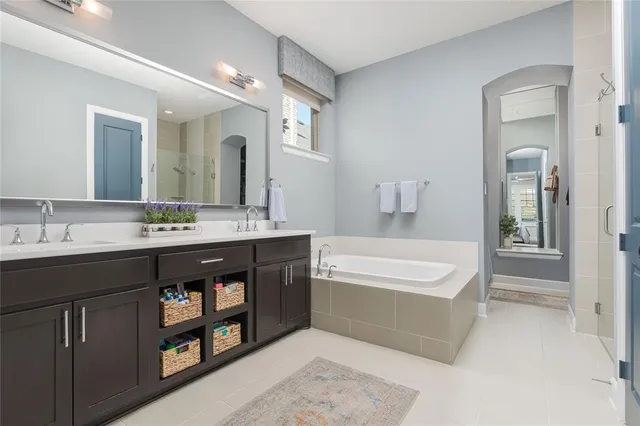 a spacious bathroom with a tub double sink and a mirror
