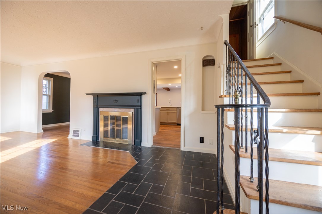 3797 Northwood Road Cleveland, OH 44118 - Photo 21 of 49 Unfurnished living room with dark wood-style flooring, arched walkways, stairway, a tile fireplace, and recessed lighting