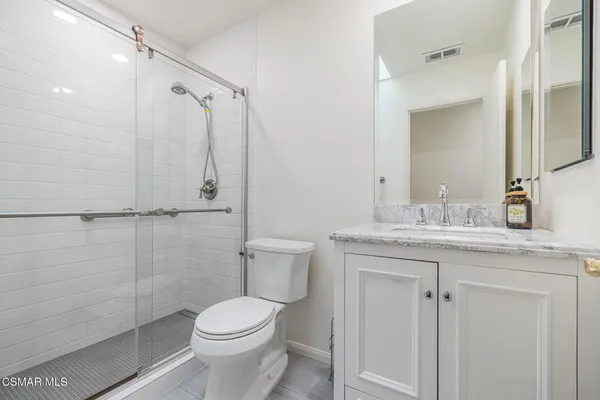 a bathroom with a granite countertop toilet sink shower and mirror