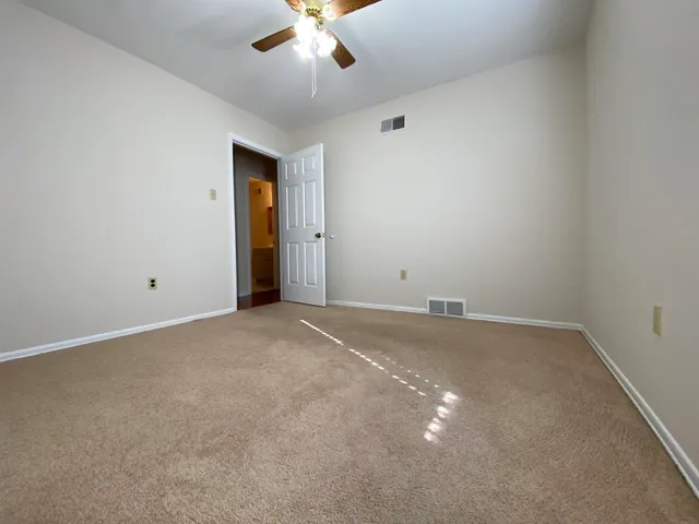 an empty room with a chandelier fan and windows