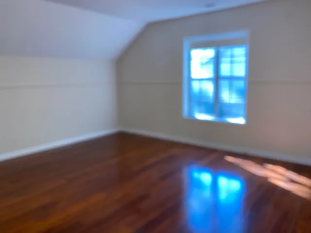an view of empty room with wooden floor and fan