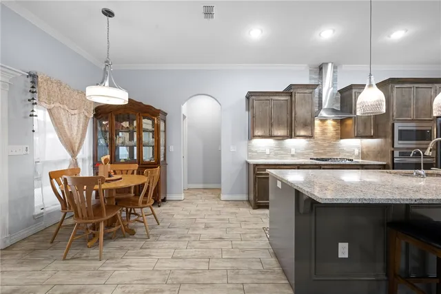 a kitchen with stainless steel appliances granite countertop a stove a sink a table and chairs