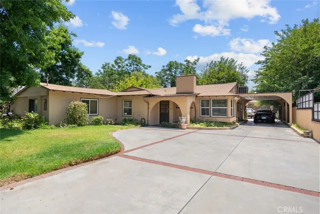 a front view of a house with a garden and trees