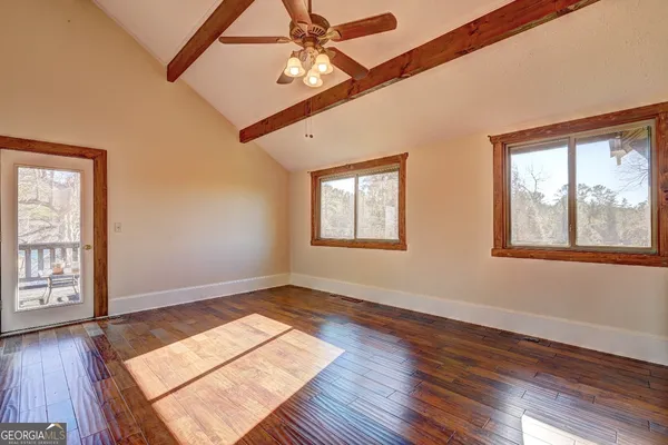 an empty room with wooden floor closet and windows