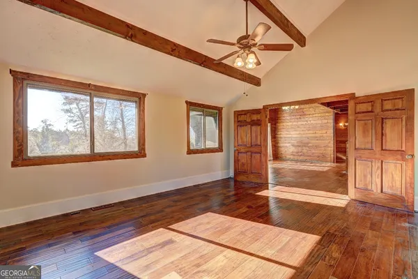 a view of an empty room with wooden floor and a window