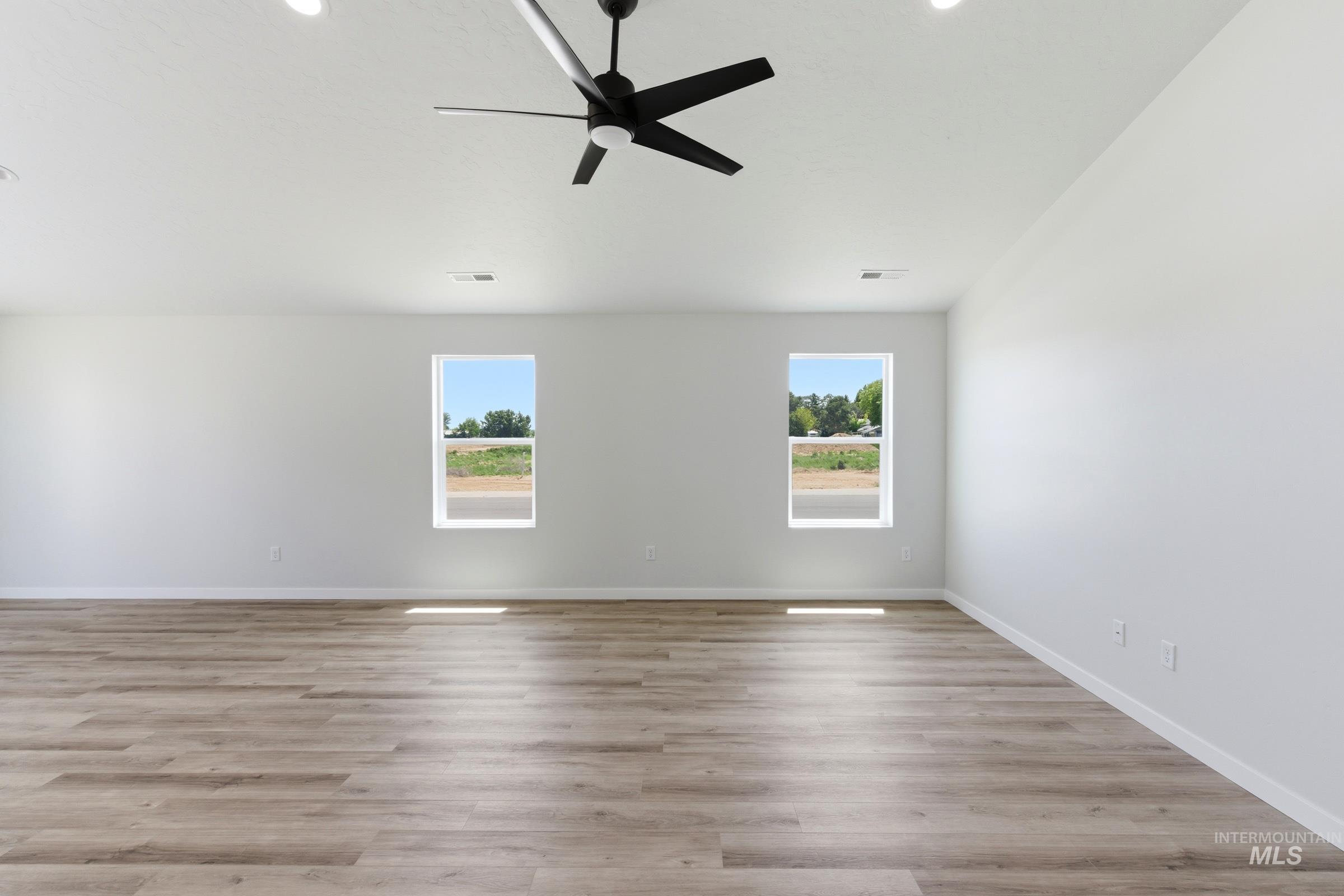 8317 South Tyrion Way Kuna, ID 83634 - Photo 6 of 22 Spacious room featuring wood-finish flooring, two large windows, a ceiling fan, and recessed lighting