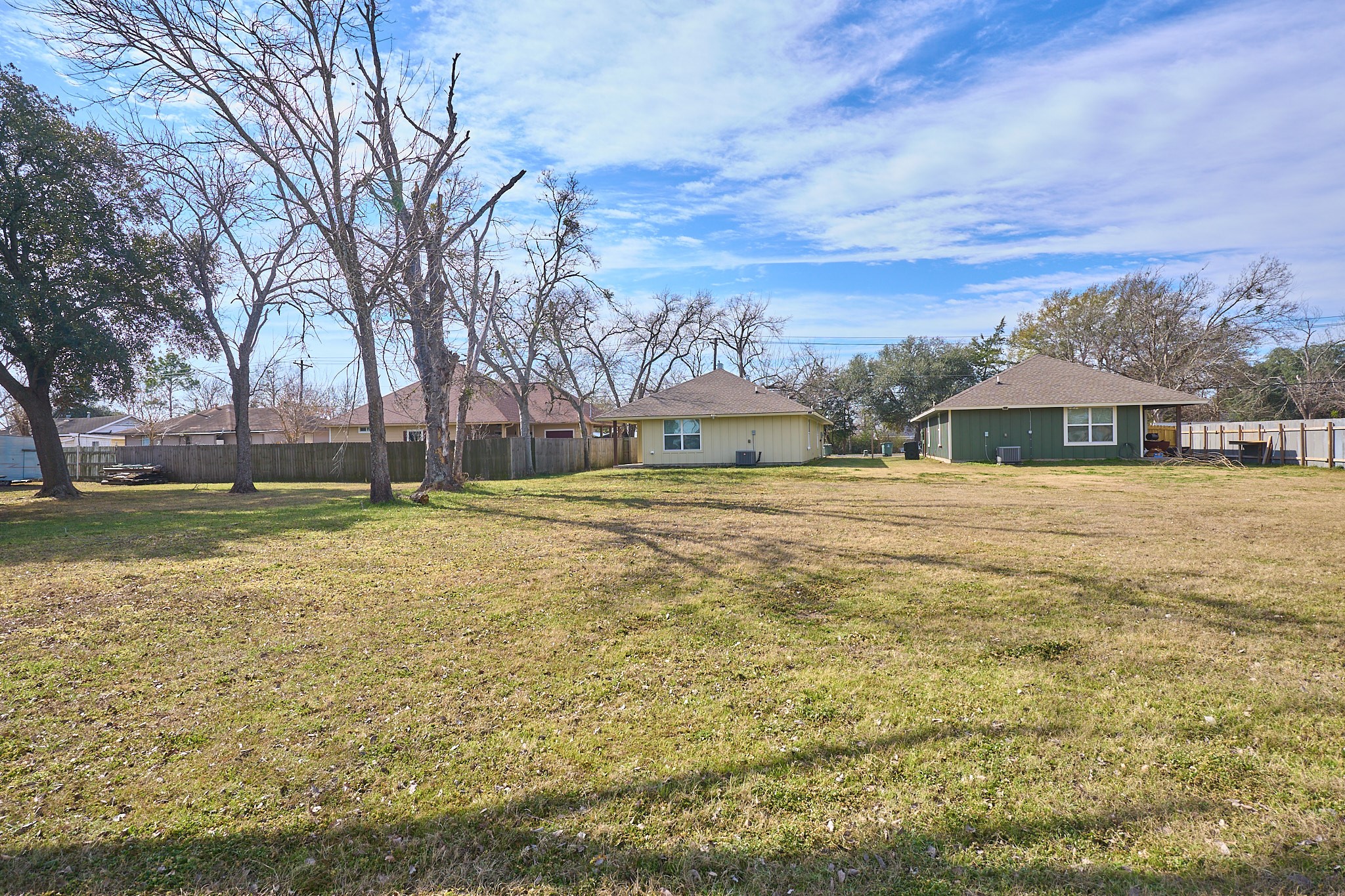 1807 Nuches Lane Bryan, TX 77803 - Photo 26 of 27 Spacious open lot with two single-story homes, surrounded by trees and a fence, offering ample yard space and potential for landscaping.
