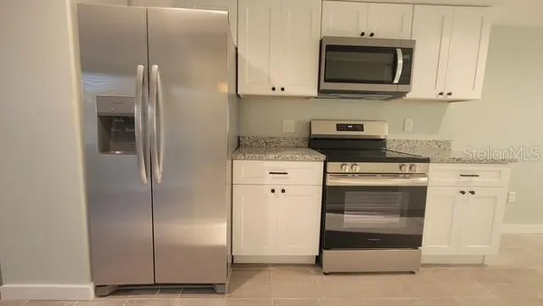 a kitchen with stainless steel appliances white cabinets and a stove a refrigerator with wooden floor