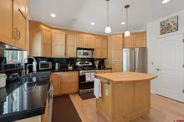 a kitchen with stainless steel appliances granite countertop a stove a sink and a microwave