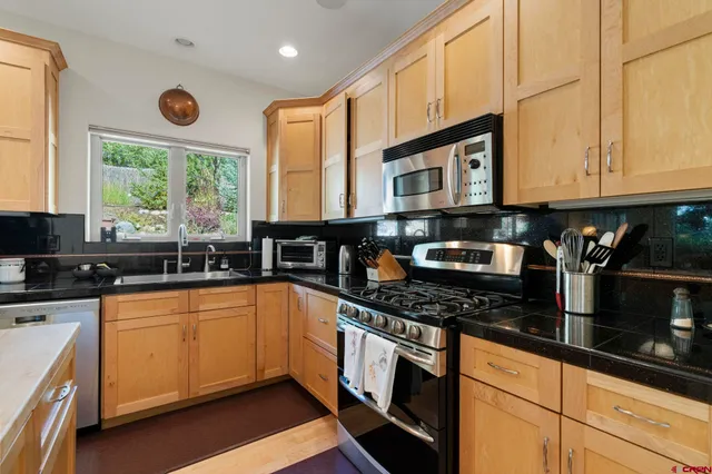 a kitchen with stainless steel appliances granite countertop a stove a sink and a microwave