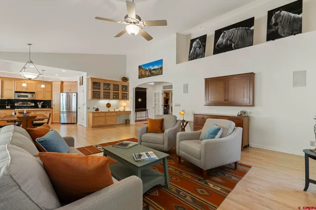a living room with furniture kitchen view and a chandelier