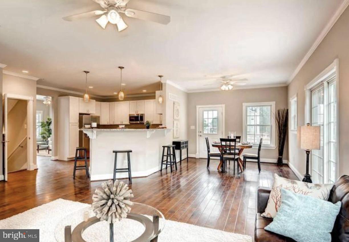 a living room with furniture kitchen view and a wooden floor
