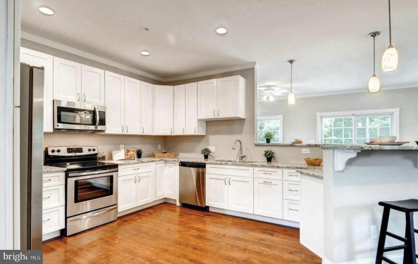 8319 Bletzer Road Baltimore, MD 21222 - Photo 2 of 7 a kitchen with stainless steel appliances a sink a stove a microwave a center island and cabinets